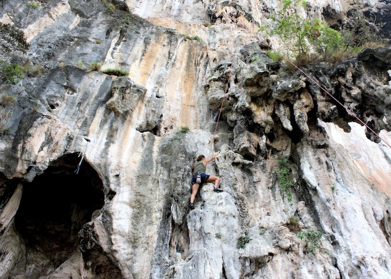 View of woman rock climbing in Thailand from below