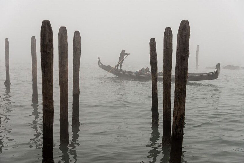 Guests cruising in Italy on a gondola during some heavy fog in Venice
