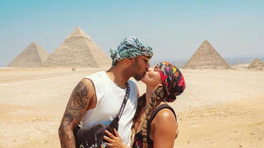 Couple kisses with Pyramids of Giza in the background