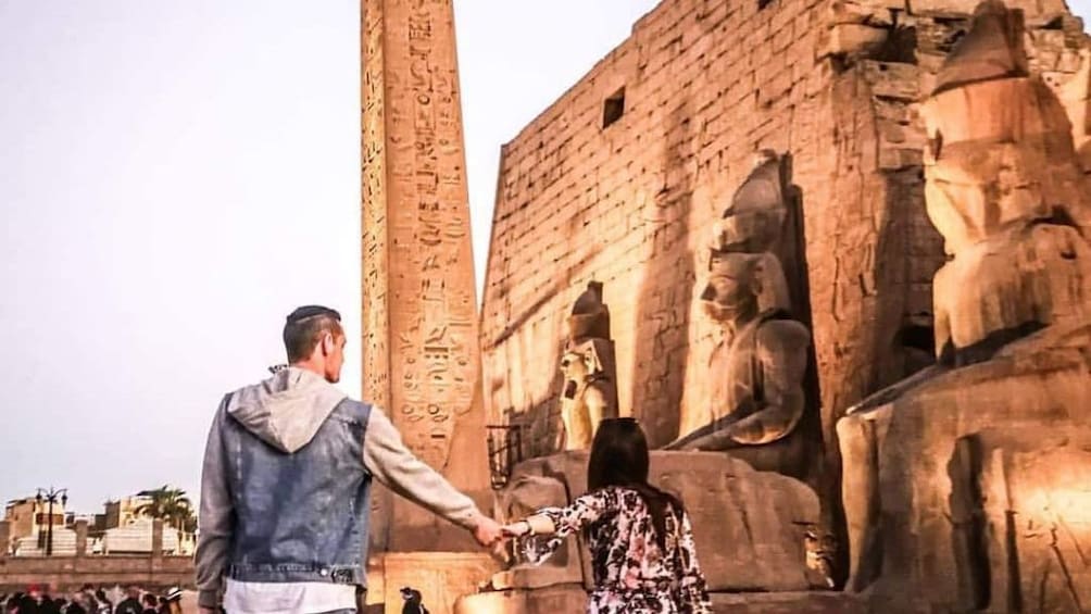 Couple hold hands in front of Luxor Temple