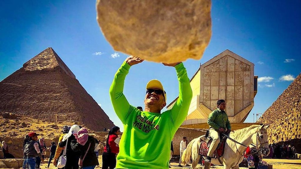 Man pretends to hold up boulder in Giza, Egypt