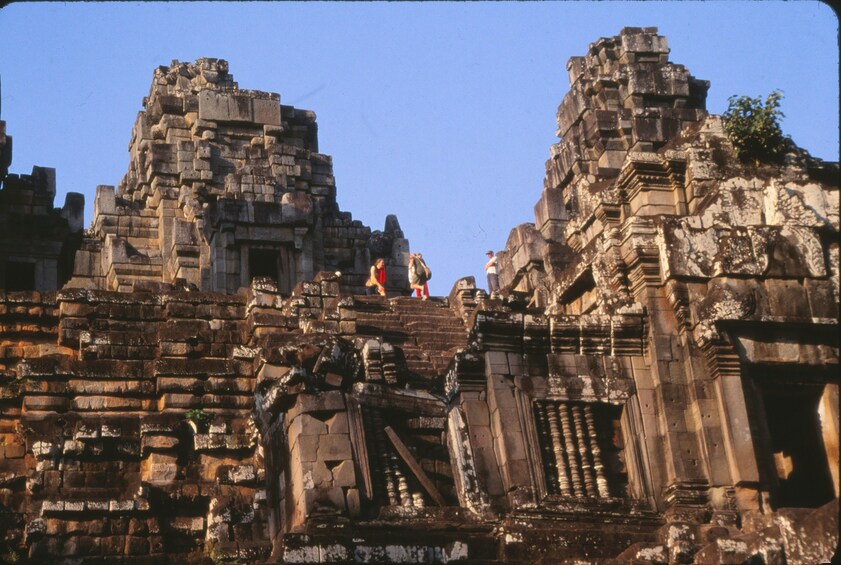 Tourists stand on top of Angkor Thom Temple on a sunny, clear day 