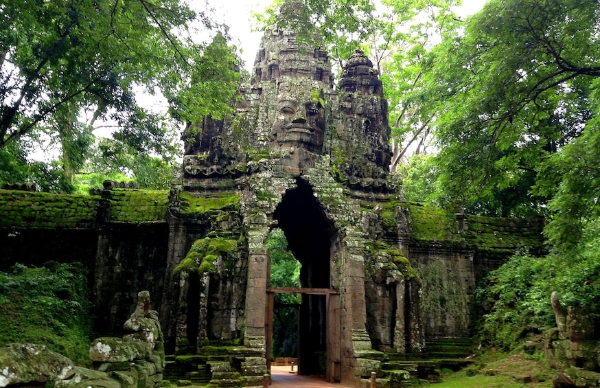 Angkor Thom front gate surrounding by bright green trees 
