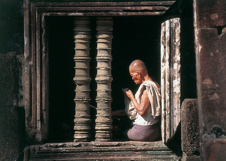 Man stands in window of building at Angkor Wat in Cambodia