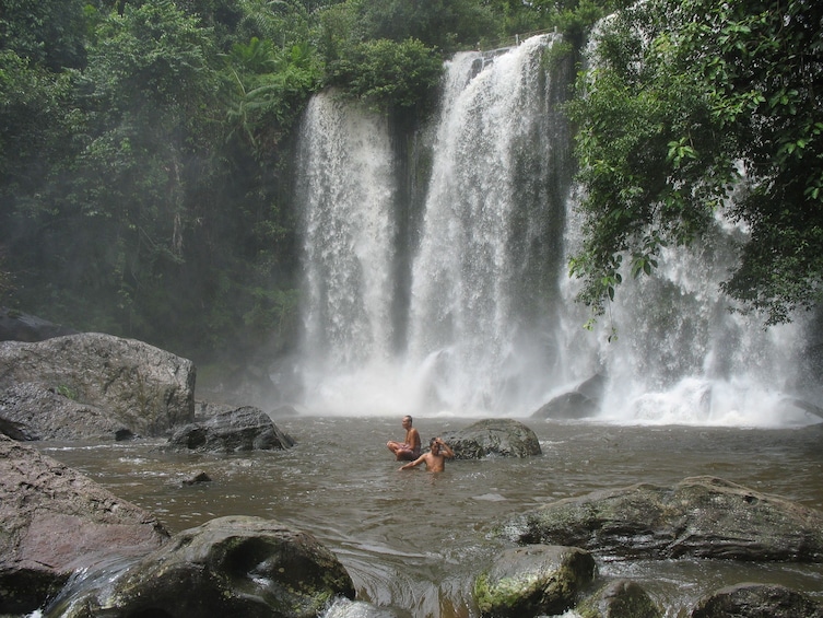 Tourists swim below Phnom Kulen Waterfall in Cambodia
