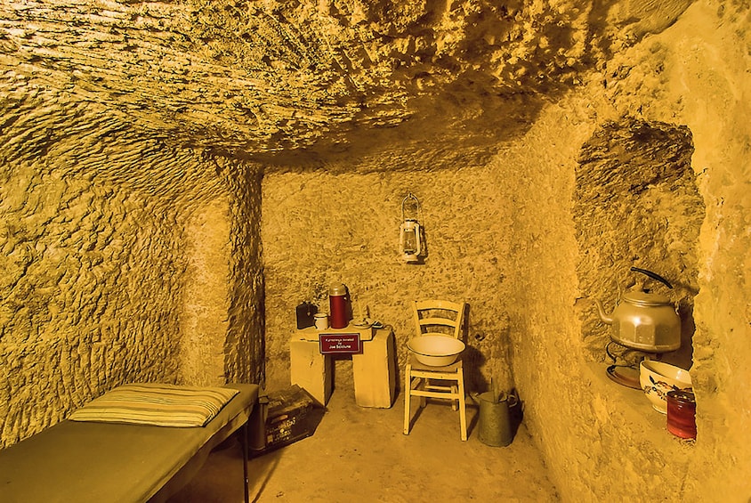 Small room with bed and chair in Mellieha Air Raid Shelter