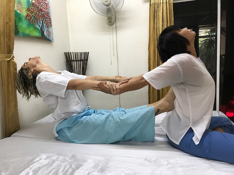 Woman with feet on partner's back stretches partner's arms