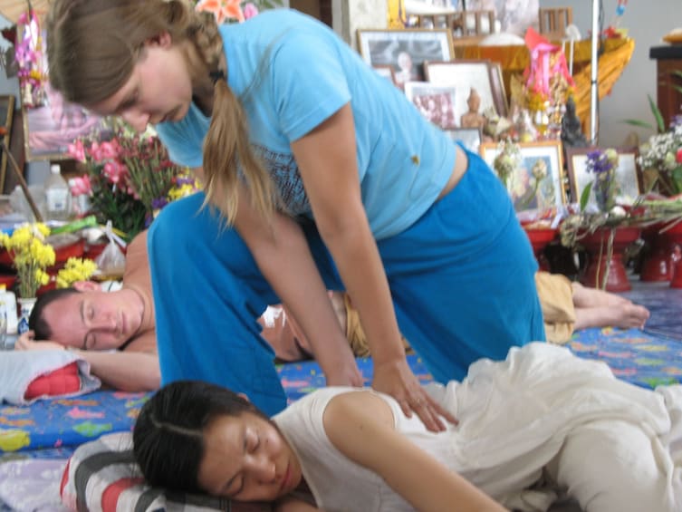 Kneeling woman presses on other woman's back with both hands