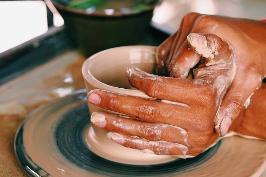 Closeup of hands making pottery on wheel