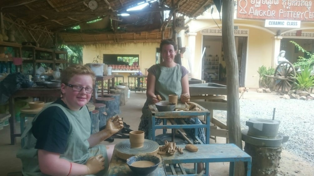 Mother and son pose while making pottery in Cambodia