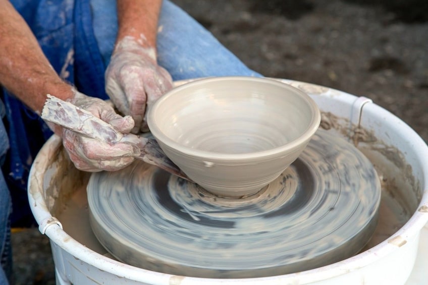 Closeup of hands creating a bowl on a pottery wheel