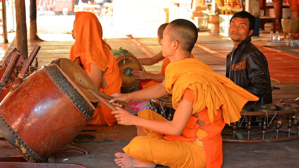 Seated monk plays large drum in Siem Reap, Cambodia