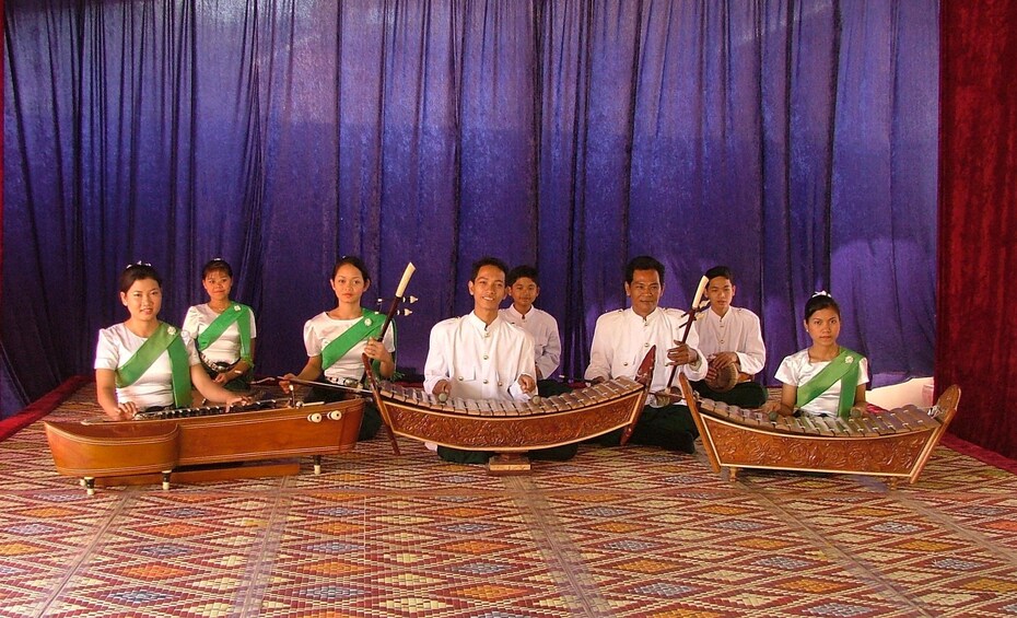 Seated group of men and women pose with traditional instruments