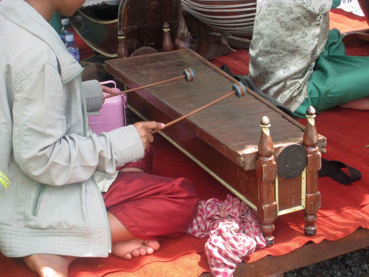 Closeup of seated woman playing Cambodian xylophone