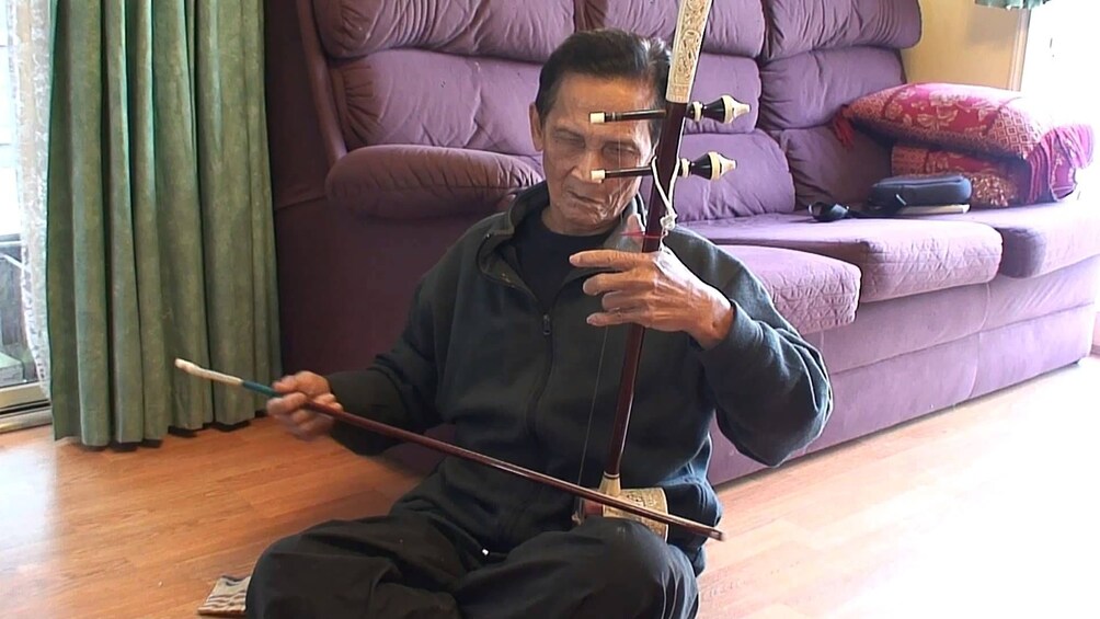 Older man plays string instrument in Siem Reap, Cambodia