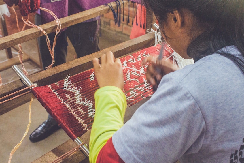 Closeup of woman weaving red silk