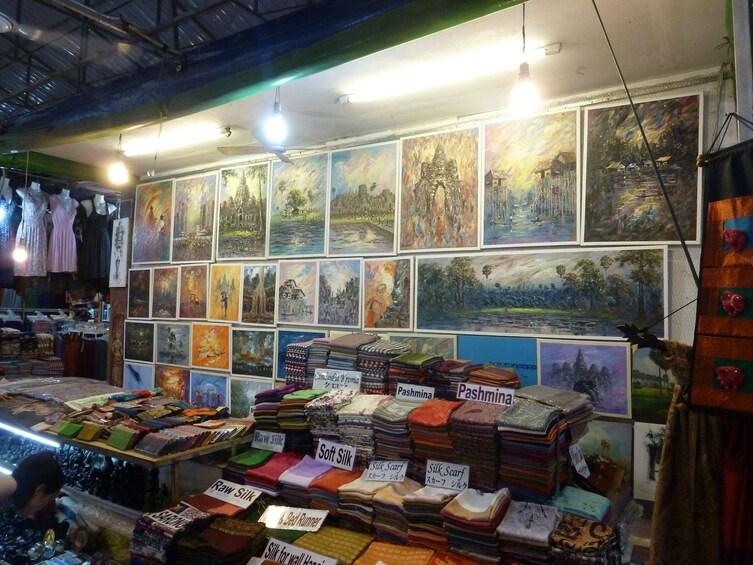 Sale display of small paintings and silk pashminas in Cambodia 