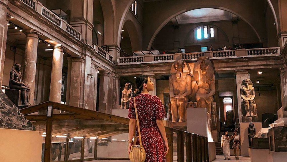 Woman in dress looks around large room of Egyptian Museum