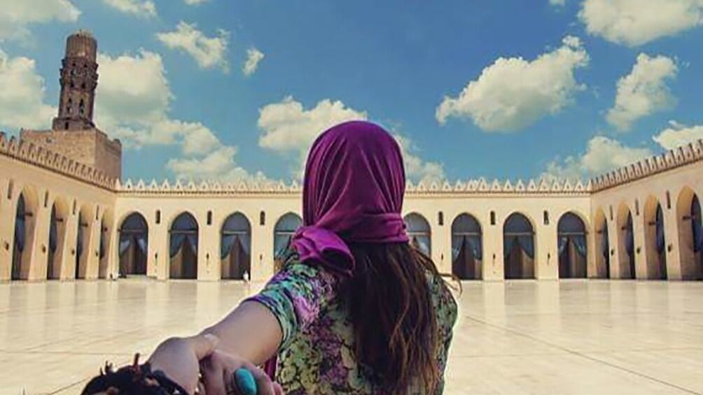 Woman leads partner towards plaza in Egypt on a sunny day