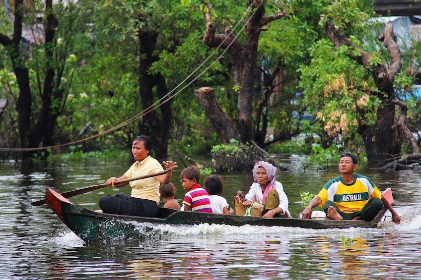 Locals on a wooden boat cruising down a lake in Kampong Phluk