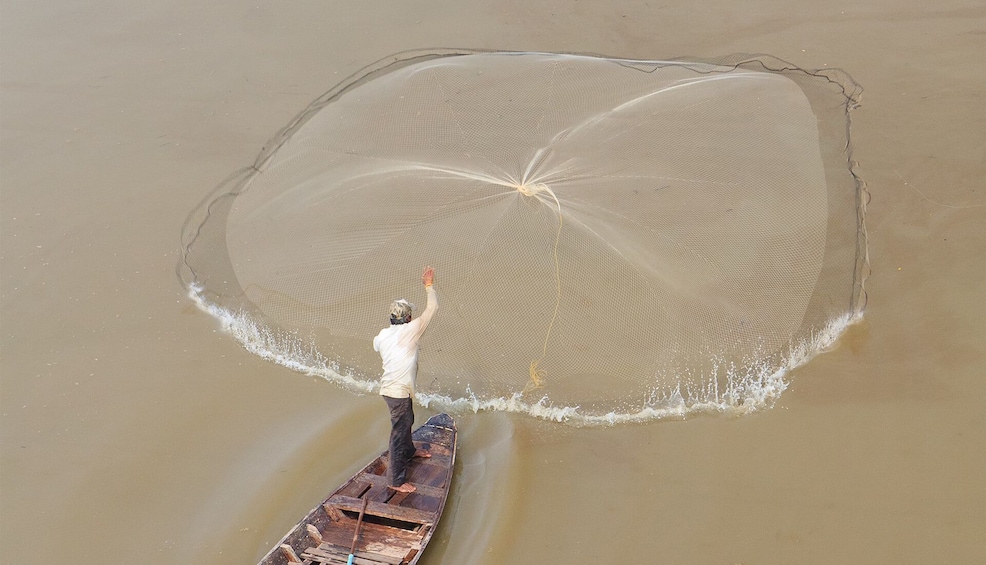 Local man throwing the fishing net into the waters of Kampong Khleang in Cambodia 