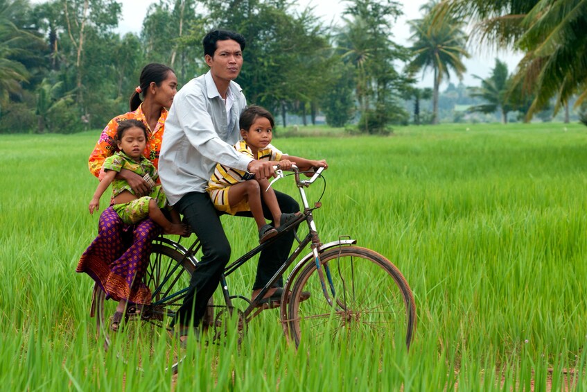 Family biking through the green grass of Luang Prabang