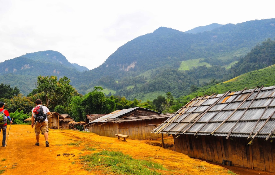 Dirt road and buildings of Khmu Village with mountains in the background