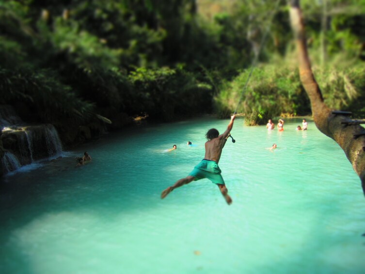 Man jumping into the refreshing pools of Kuang Si Waterfall