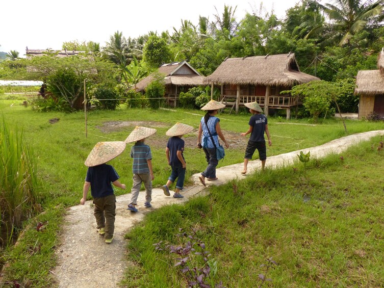 Mother and children walk along path through farmland in Laos