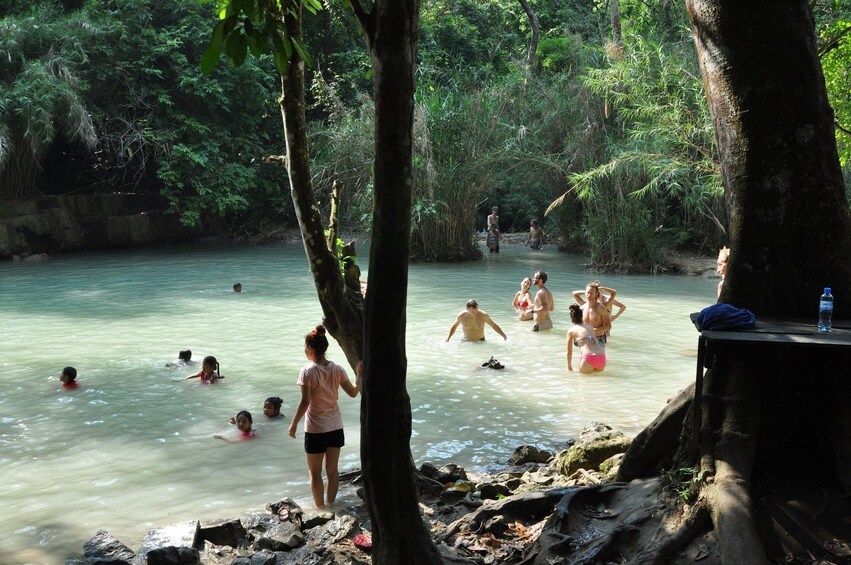 People swim and play in waters beneath Kuang Si Falls in Laos