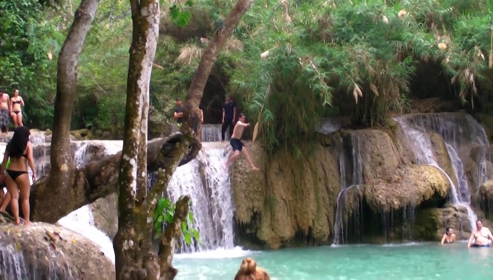 Tourists jump off of top of Kuang Si Waterfall in Laos