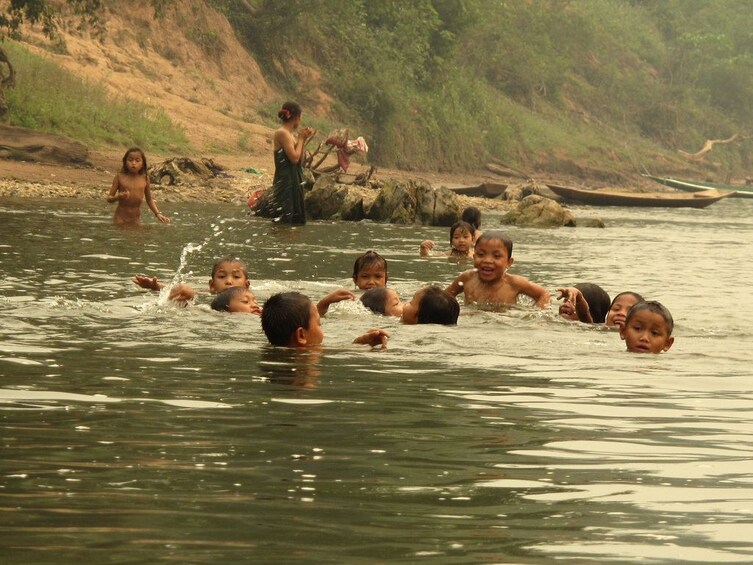 Group of young children swim in the Nam Ou River in Laos