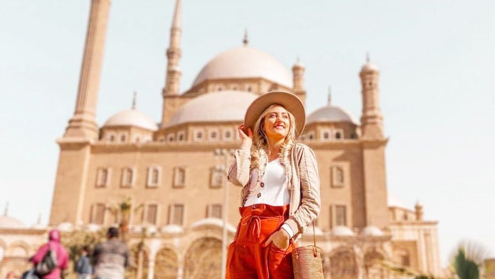 Woman in large hat poses in front of the Mosque of Muhammad Ali