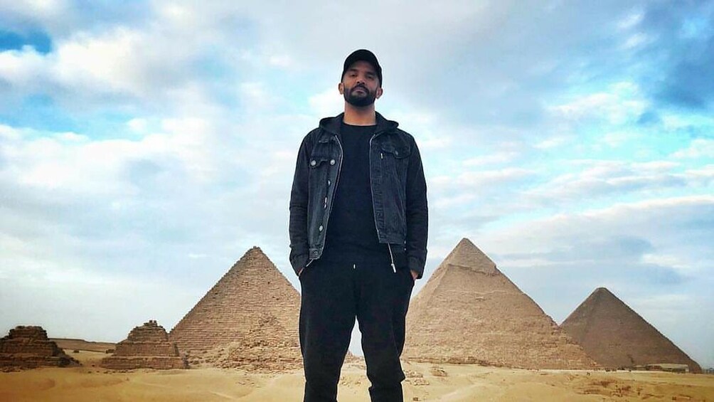 Man poses in front of the Pyramids of Giza