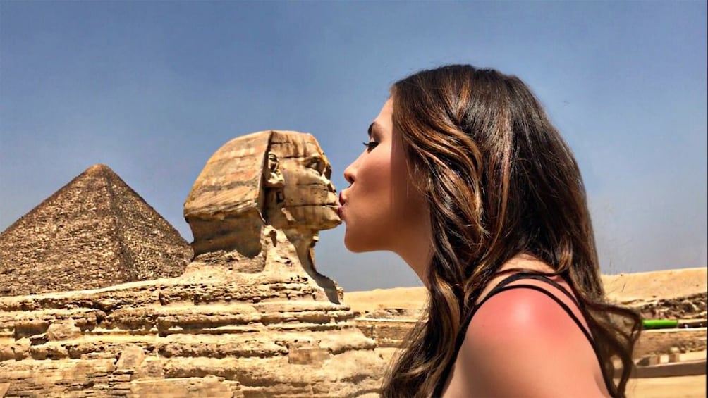 Closeup of woman pretending to kiss Sphinx in Giza, Egypt