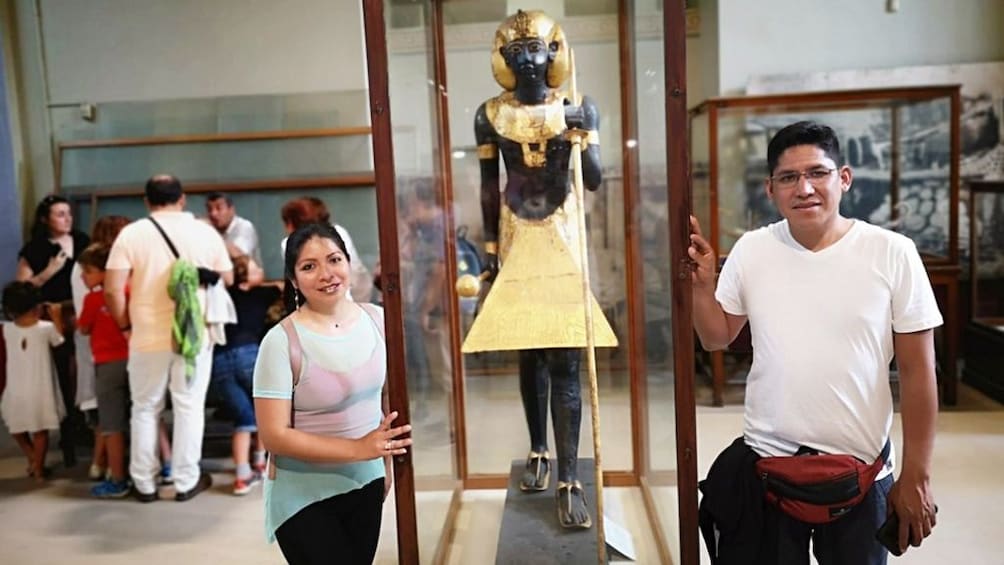 Man and woman pose with small pharaoh statue at the Egyptian Museum