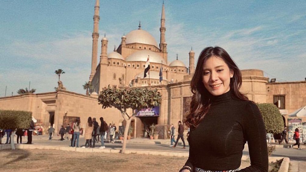 Woman poses in front of the Mosque of Muhammad Ali on a sunny day