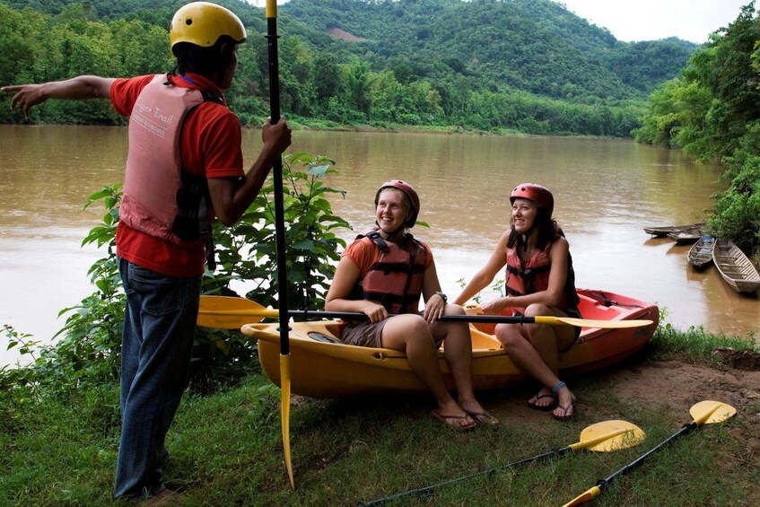 Instructor speaks to tourists preparing to kayak in Nam Khan River