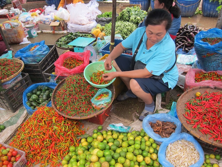 Woman with bowls of bright red peppers and limes at Luang Prabang morning market