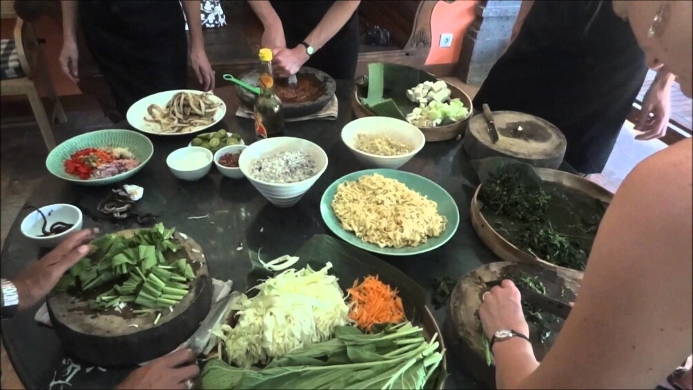Tourists prepare balinese food on a large round table
