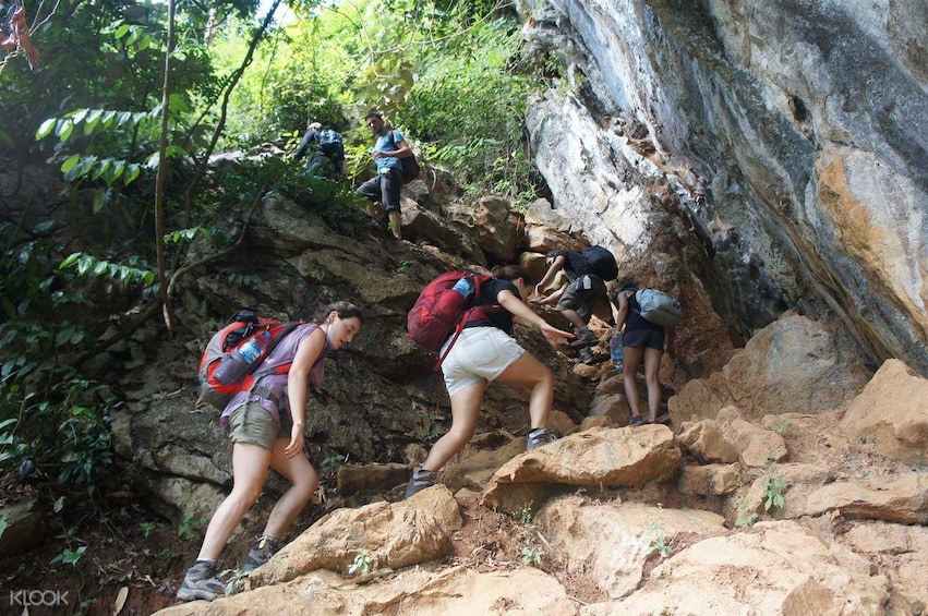 Group walk up steep rocky trail in Vang Vieng, Laos