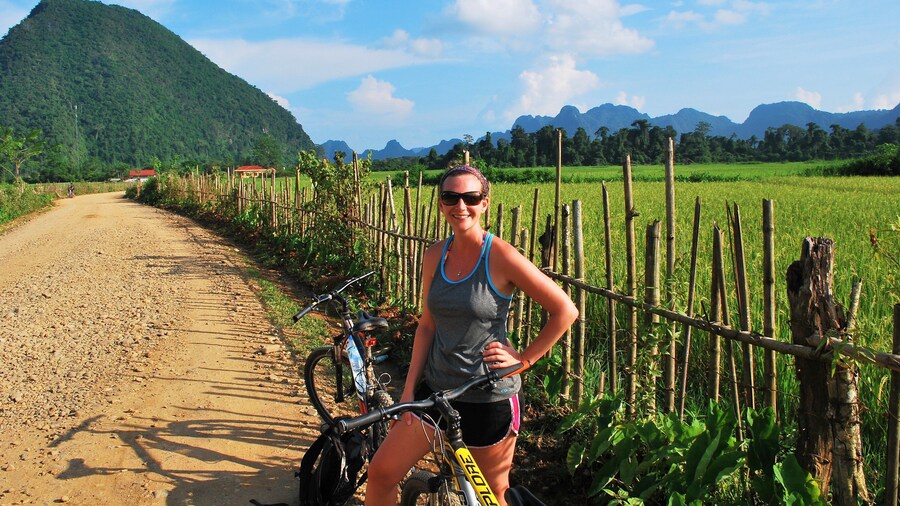 Woman poses on bike on sunny day in Vang Vieng, Laos