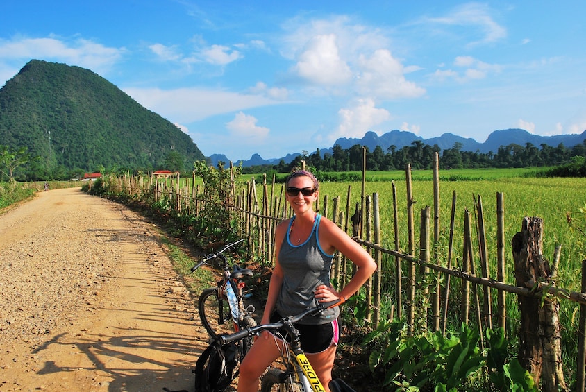 Woman poses on bike on sunny day in Vang Vieng, Laos