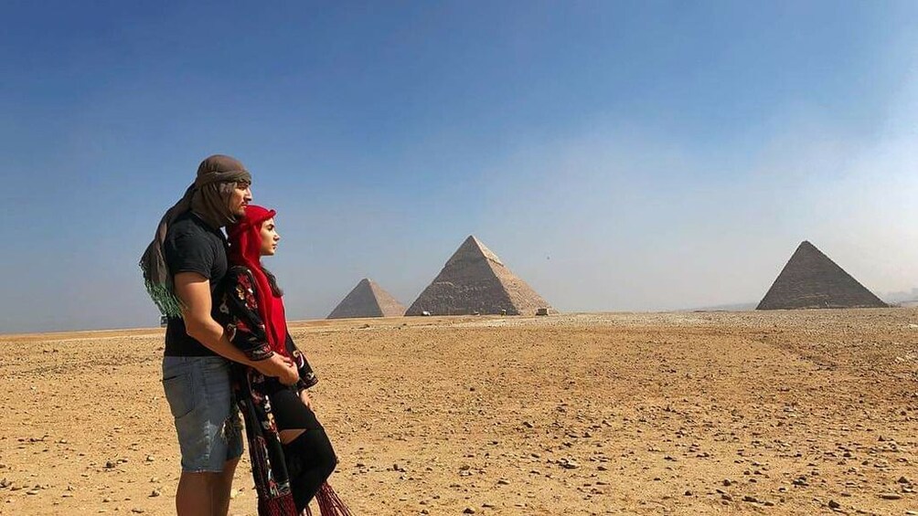 Couple stand together with Pyramids of Giza in the background
