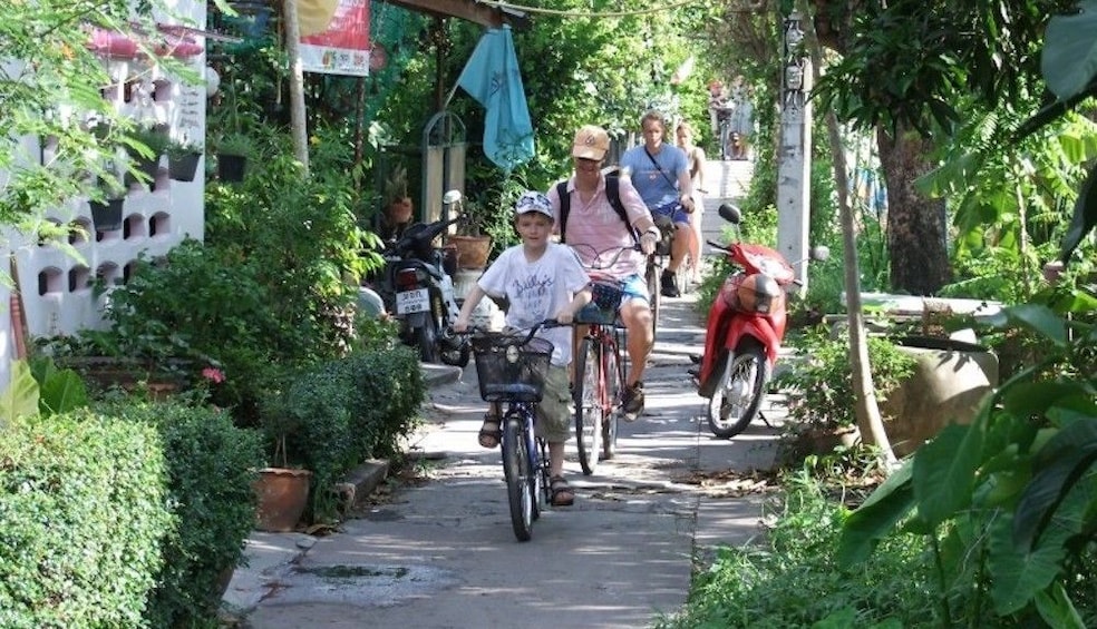 Parents and kids bike through pathway among in Bangkok, Thailand