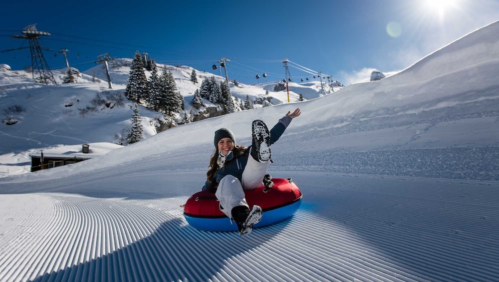 Person inner tubing down a ski slope