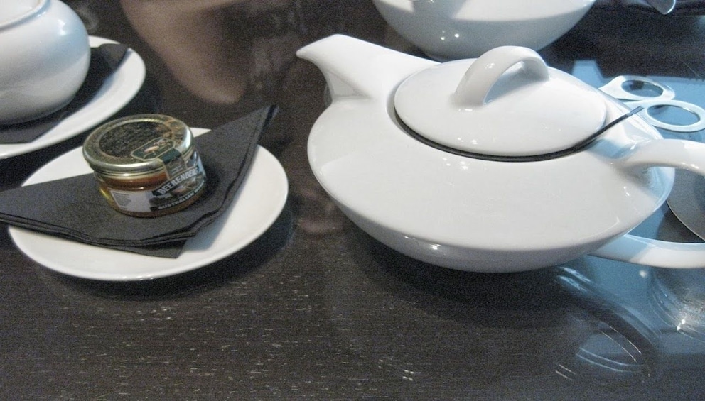 White tea pot with plate with small jar of honey