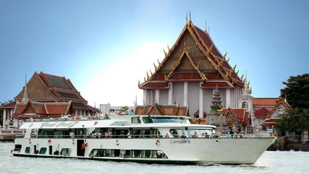 Cruise ship on Chao Phraya River with Wat Kanlayanamit in the background