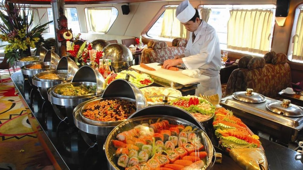 Large sushi buffet with chef behind the counter cutting sushi in Thailand