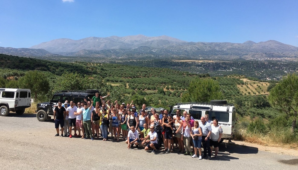 Large group pose with Land Rovers and Rhodes landscape 